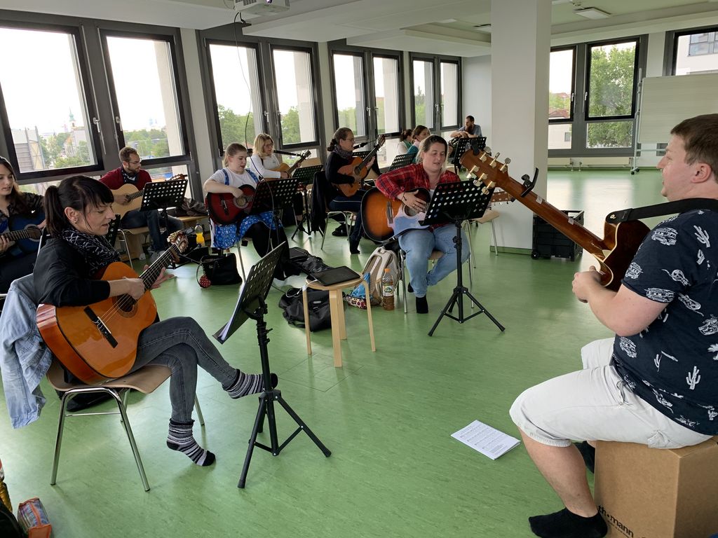 Erzieher-Schüler sitzen nebeneinander und spielen Gitarre.