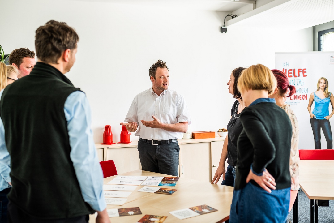 Mehrere Teilnehmende stehen in einem Kreis und führen Gespräche mit dem Seminarleiter.