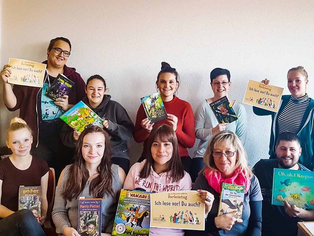 Bundesweiter Vorlesetag - Erzieher des Bildungswerkes sind dabei Zehn junge Frauen und Männer schauen in die Kamera und halten Kinderbücher in den Händen. Am Vorlesetag lesen sie in einer Schule daraus vor.
