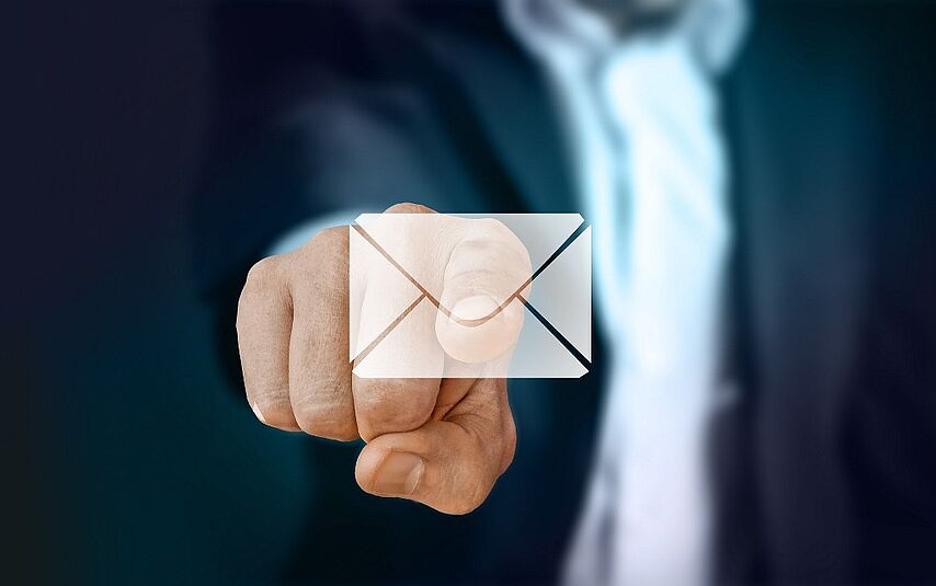 Newsletter Ein Mann im Anzug zeigt auf den Betrachter des Bildes. Am Ende seines Zeigefingers ist eine E-Mail dargestellt.