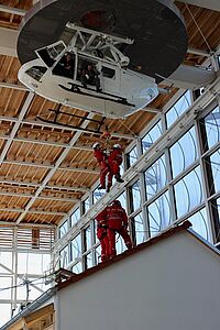 Jugendliche der Bergwacht seilen sich in einer Übungshalle von einem in der Luft hängenden Helicopter ab.