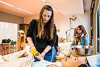 Eine Auszubildende erlernt die Pflege eines Patienten. Eine Lehrpuppe im Krankenhausbett kommt dabei zum Einsatz.