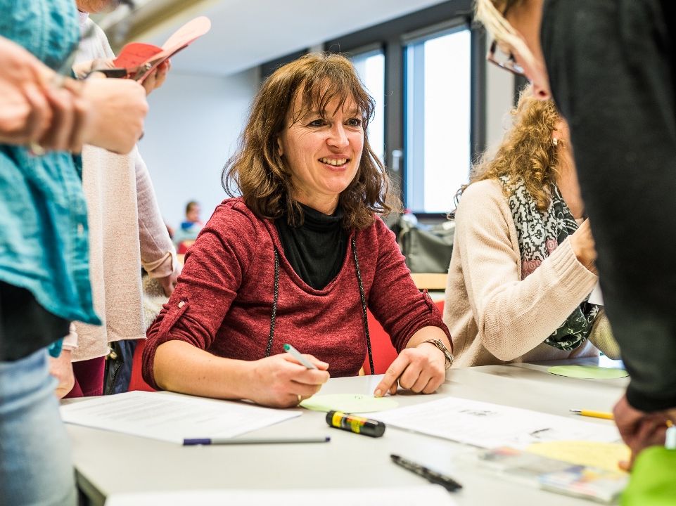 Erzieher-Ausbildung Mehrere Auszubildende stellen Material für zur Beschäftigung von Personen unterschiedlicher Altersklassen zusammen.