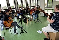 Erzieher-Schüler sitzen nebeneinander und spielen Gitarre.
