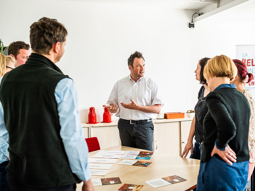Mehrere Teilnehmende stehen in einem Kreis und führen Gespräche mit dem Seminarleiter.
