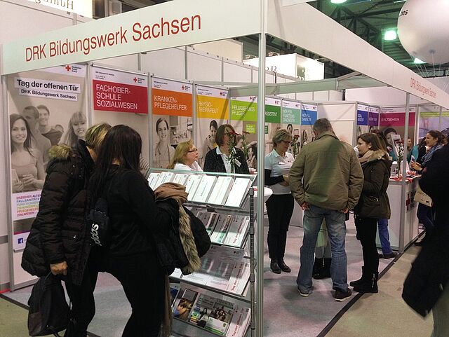 Der Informationsstand des Bildungswerkes Sachsen ist auf der Messe Karriere Start zu sehen. Einige Interessierte schauen sich um und sprechen mit den Anwesenden vom Bildungswerk.