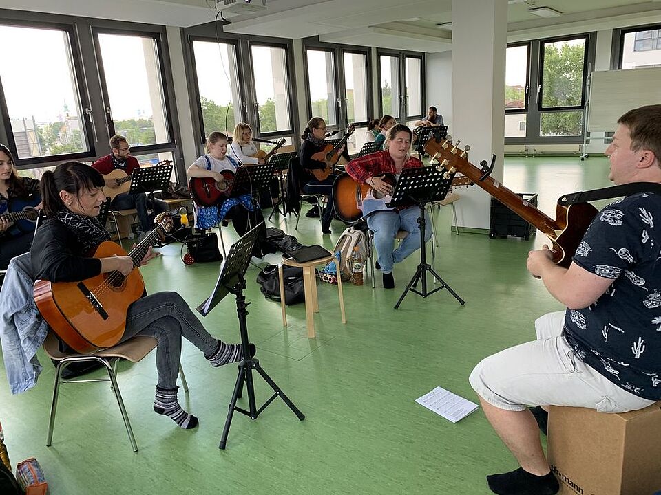 Erzieher-Schüler sitzen nebeneinander und spielen Gitarre.