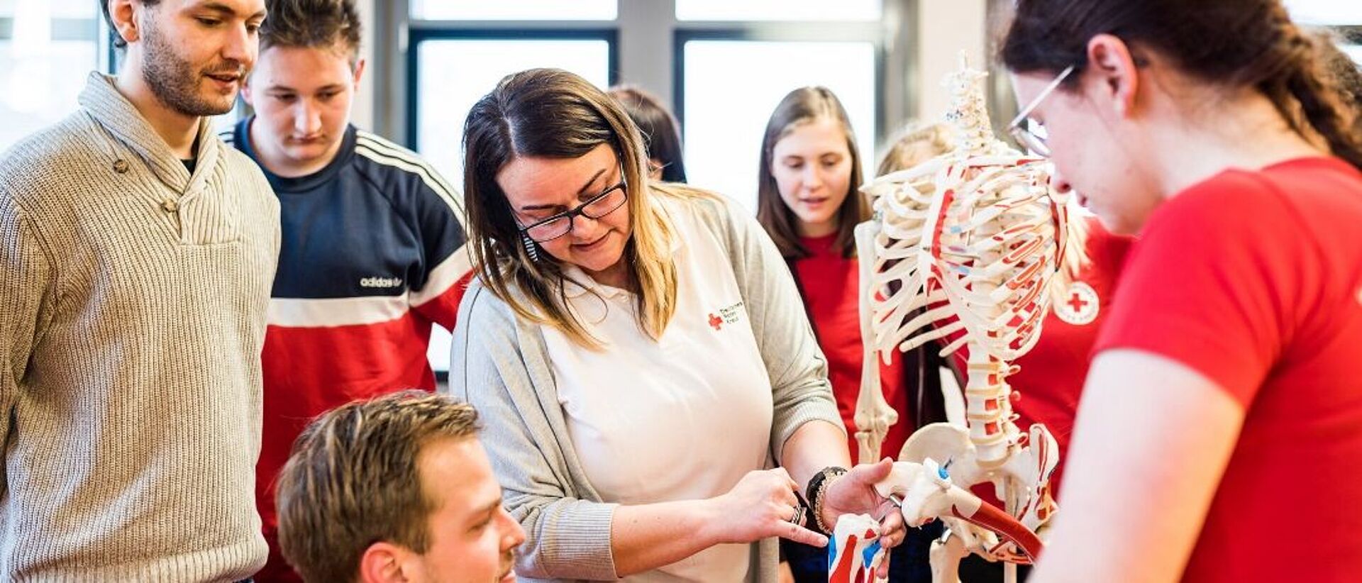 Die Dozentin erklärt den Auszubildenden anhand eines Skeletts den Aufbau und Funktionsweise des menschlichen Körpers.