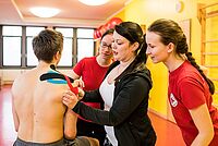 Eine Dozentin zeigt den Auszubildenden, wie man einen Patienten tapt.