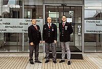 Der neue Landesleiter der Bereitschaften sowie seine zwei Stellvertreter stehen vor dem DRK Zentrum und lächeln in die Kamera.